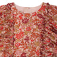 Close-up of the Girls' Lizzy Dress with Ruffles in Liberty Fabric by Bonpoint, featuring a pink base with a bold red, orange, and yellow floral print and vertical ruffle details on each side.