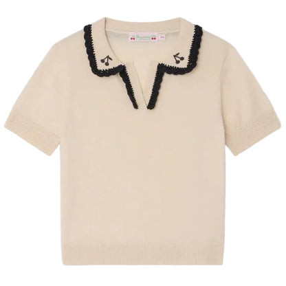 The Bonpoint Girls' Lisette Sweater features short sleeves, a cream knit, a scalloped black-trimmed notched lapel collar, and delicate hand-embroidered cherries near the neckline.