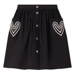 The Bonpoint Girls' Lierre Hand-Embroidered Skirt is black with front buttons and two large front pockets, each adorned with delicate white hand-embroidered hearts.