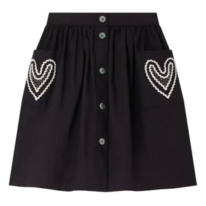 The Bonpoint Girls' Lierre Hand-Embroidered Skirt is black with front buttons and two large front pockets, each adorned with delicate white hand-embroidered hearts.