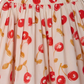 The Girls' Suzon Skirt by Bonpoint is a light-colored organic cotton skirt with a gathered waist and a red cherry print with green leaves.