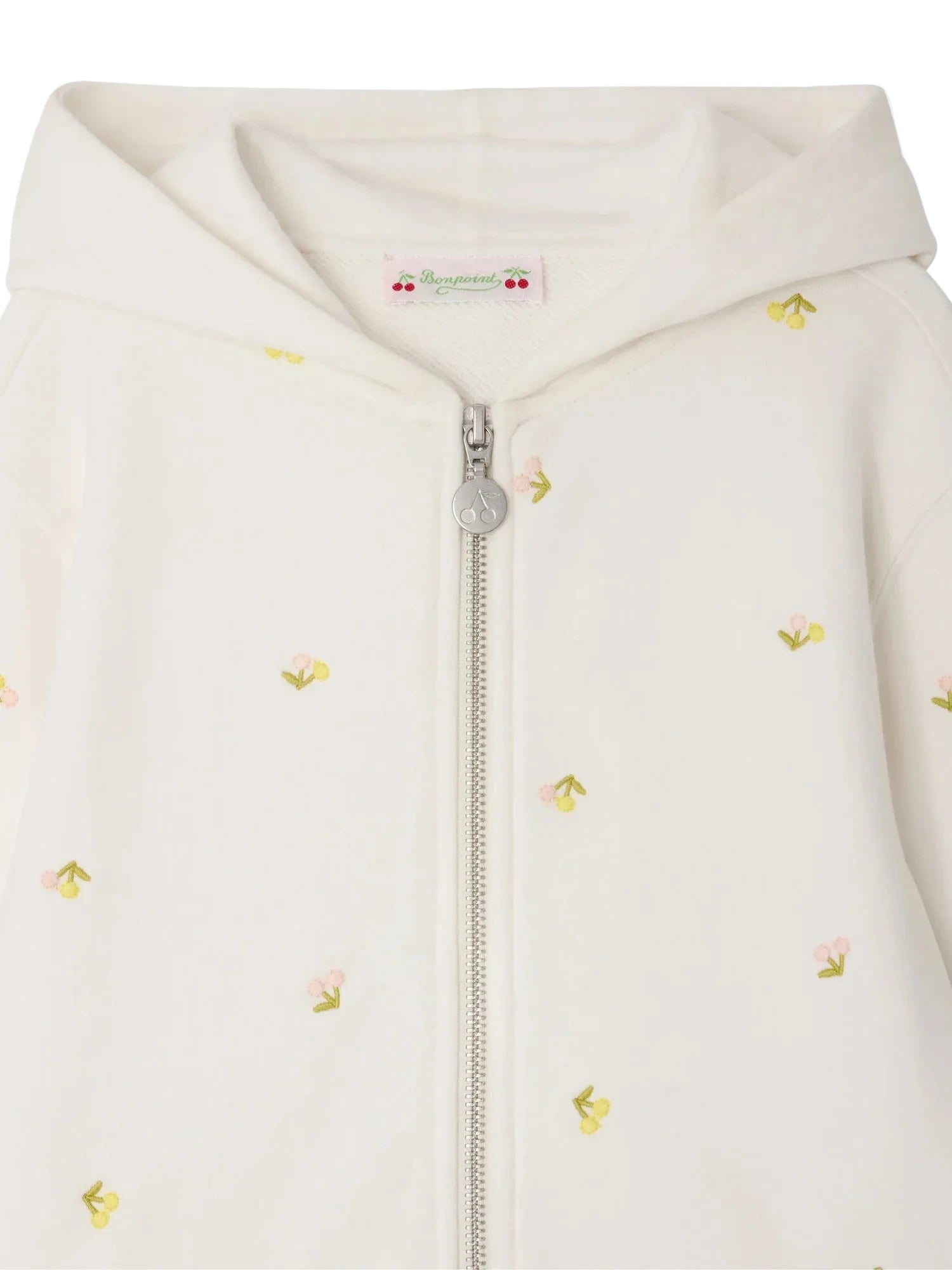 Close-up of the Bonpoint Girls' Talent Hoodie, a zip-up sweatshirt made from organic cotton fleece, adorned with delicate cherry embroidery on soft white fabric.