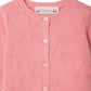 The Baby Girls' and Girls' Teyana Cardigan by Bonpoint is a pink knitted cardigan made from organic cotton, featuring a cherry pattern, button-up front, and a signature Bonpoint label at the collar.