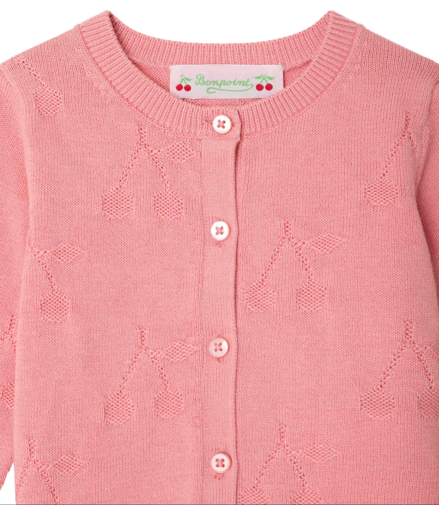 The Baby Girls' and Girls' Teyana Cardigan by Bonpoint is a pink knitted cardigan made from organic cotton, featuring a cherry pattern, button-up front, and a signature Bonpoint label at the collar.