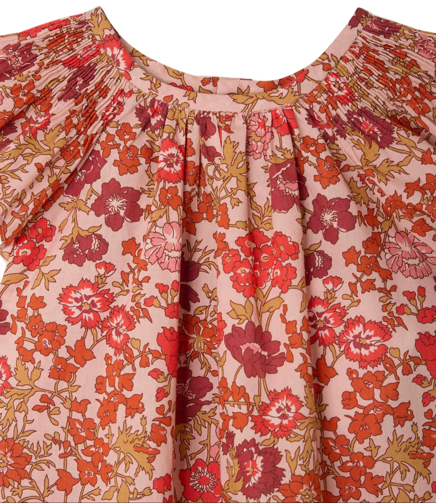 Close-up of Bonpoint's Baby Girls' and Girls' Carmella Smocked Dress in pink with a red, orange, and white floral Liberty print, featuring smocked details at the neckline and gathered shoulders.