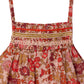 Close-up of Bonpoint's Baby Girls' Lilisy Dungarees in Liberty fabric, featuring thin straps, a floral red, pink, and brown print, and hand-embroidered smocking on the bodice for an artisanal finish.