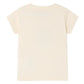 The Bonpoint Baby Boys' Tom T-Shirt, a plain short-sleeved beige tee made from soft cotton jersey, is shown laid flat with the back side facing up.