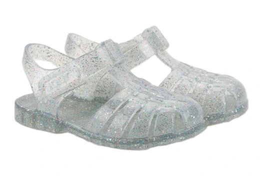 The Igor Clasica Cristal Sandal is a pair of translucent jelly shoes with glitter, Scandi-inspired colors, closed toes, flexible soles, and ankle straps.