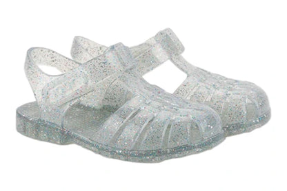 The Igor Clasica Cristal Sandal is a pair of translucent jelly shoes with glitter, Scandi-inspired colors, closed toes, flexible soles, and ankle straps.
