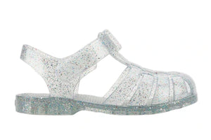 The Igor Clasica Cristal Sandal is a flexible, clear jelly sandal with silver glitter, a closed toe, ankle strap, and flat sole.