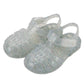 The Igor Clasica Cristal Sandal is a pair of flexible, translucent glitter jelly shoes with closed toes and ankle straps, shown on a white background.
