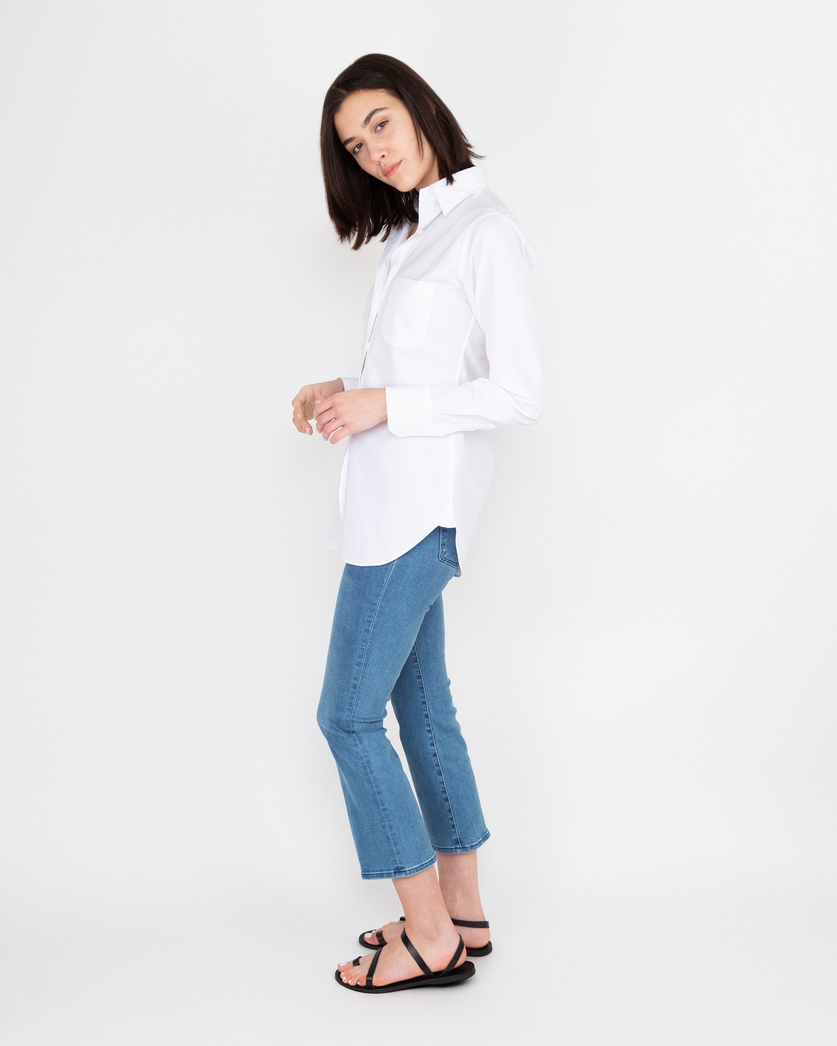 Woman posing in an Ann Mashburn Boyfriend Shirt, blue jeans, and black sandals against a plain background.