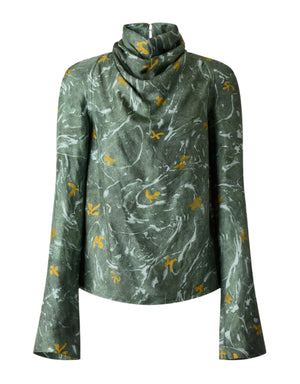 The Altuzarra Cara Top is a green high-neck turtleneck with long bell sleeves and a marbled pattern featuring small yellow floral designs, reflecting Altuzarra's signature style.