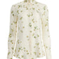 The Chika Top by Altuzarra is a cream silk, long-sleeve button-down with green and yellow floral print, pointed collar, and cuffed sleeves for a relaxed look.