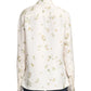 A person wearing the Altuzarra Chika Top, a relaxed silk blouse with long cuffed sleeves and a light floral pattern, shown from the back.