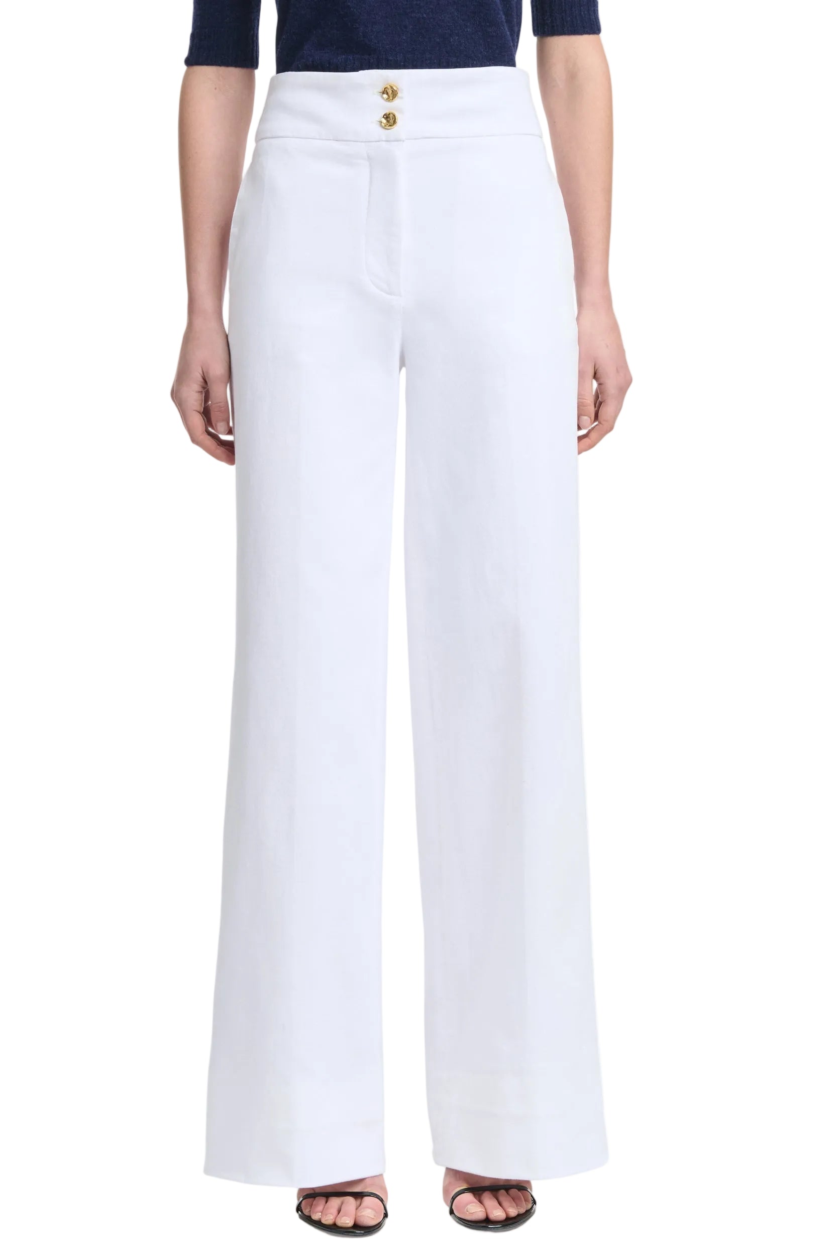 Person wearing Altuzarra's Rudy Pant in high-waisted, wide-leg white with two gold buttons, styled with a navy top and open-toe black heels.