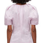 Rear view of a person wearing a pink 3.1 Phillip Lim Bloom Sleeve Scoop Neck Top with short sleeves and a yoke.