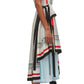 A person wearing a sleeveless 3.1 Phillip Lim Liberty Cascade Dress with vertical stripes and a belt stands sideways. The dress features a cowl neckline and an asymmetric hem. The person has a tattoo on their upper arm and is wearing black open-toe heels.