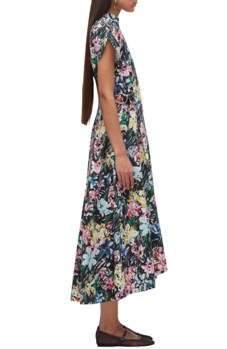 A person wearing a colorful floral-patterned A-line dress stands sideways, displaying the dress's length and short sleeves. The 3.1 Phillip Lim Flowerworks Puff Sleeve Flare Dress by 3.1 Phillip Lim is paired with black flat shoes, completing the look.