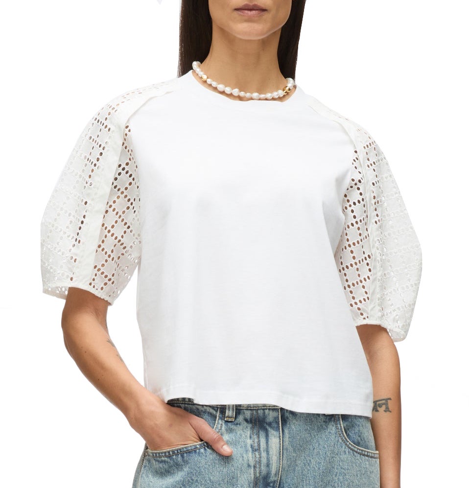 A woman stands with one hand in her pocket, wearing the 3.1 Phillip Lim Broderie Anglaise Combo T Shirt, blue jeans, and a pearl necklace.