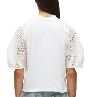 A person is seen from the back wearing the 3.1 Phillip Lim Broderie Anglaise Combo T Shirt with white eyelet lace details, paired with blue denim jeans.