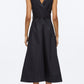 A woman faces away, wearing the 3.1 Phillip Lim Crisscross Back Midi Dress—a sleeveless, dark technical poplin V-neck dress with an A-line skirt—and black shoes, set against a plain white background.