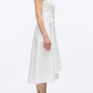 A woman stands in profile against a plain white background wearing the 3.1 Phillip Lim Crisscross Back Midi Dress with a V-neck, A-line skirt, and black sandals.
