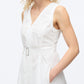 A woman models the 3.1 Phillip Lim Crisscross Back Midi Dress, a sleeveless white V-neck design with a belted waist and A-line skirt, standing with one hand in her pocket against a plain background.