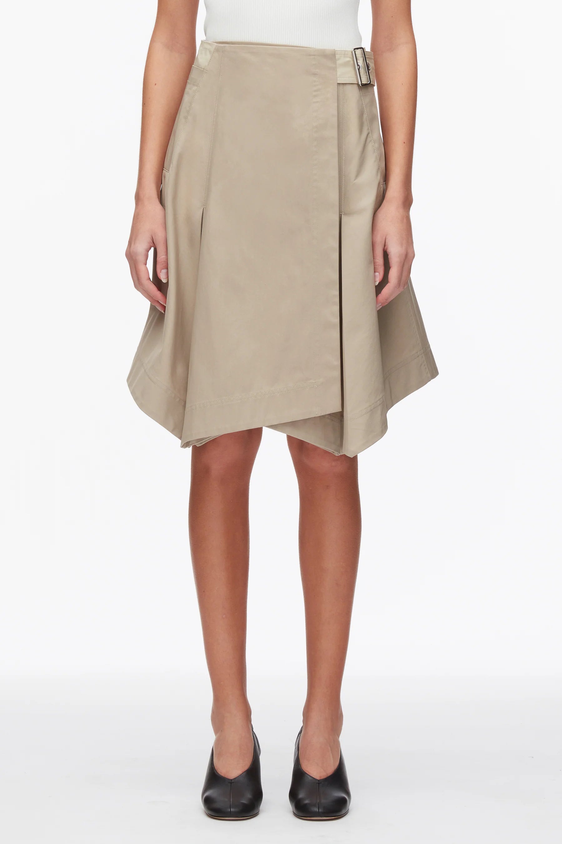 A person wears the 3.1 Phillip Lim Two-Toned Handkerchief Wrap Skirt with an architectural hemline, styled with a white top and black shoes.