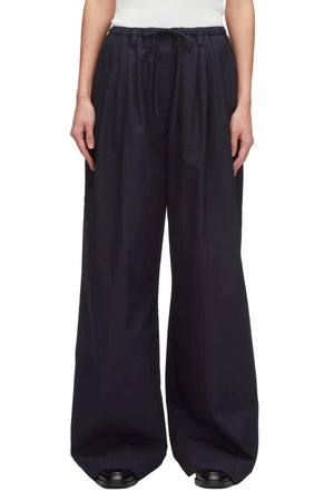 A person wears 3.1 Phillip Lim Structured Cotton Pull-On Straight Leg Pants with a white top and black shoes.