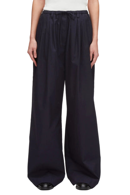 A person wears 3.1 Phillip Lim Structured Cotton Pull-On Straight Leg Pants with a white top and black shoes.