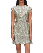A woman wears the 3.1 Phillip Lim Short Sleeve Floral Mini Dress in pale green and gray, featuring a subtle 60s silhouette as she stands against a plain background.