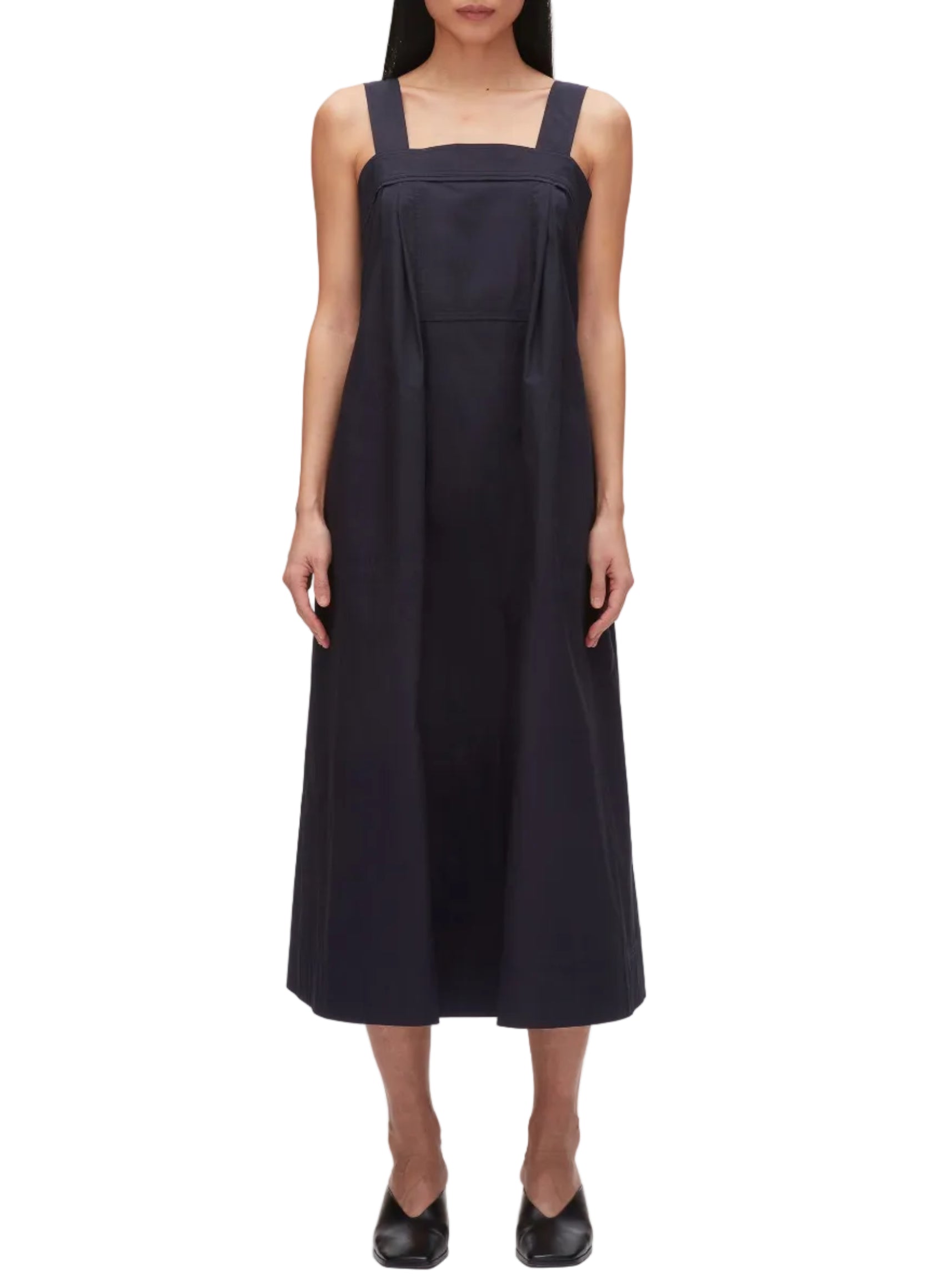 A person wears the 3.1 Phillip Lim Structured Cotton Poplin Midi Dress—sleeveless, ankle-length, dark navy with wide shoulder straps—paired with black shoes, standing against a plain white background.