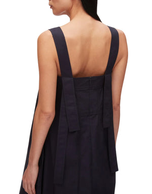 A woman wears the 3.1 Phillip Lim Structured Cotton Poplin Midi Dress, featuring a sleeveless, dark design with a square neckline, wide straps, and two long vertical panels at the back.