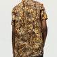 Person wearing the Charlie Top by Adam Lippes, a short-sleeve button-up with a collared silhouette and brown and yellow abstract woodgrain pattern, viewed from the back.