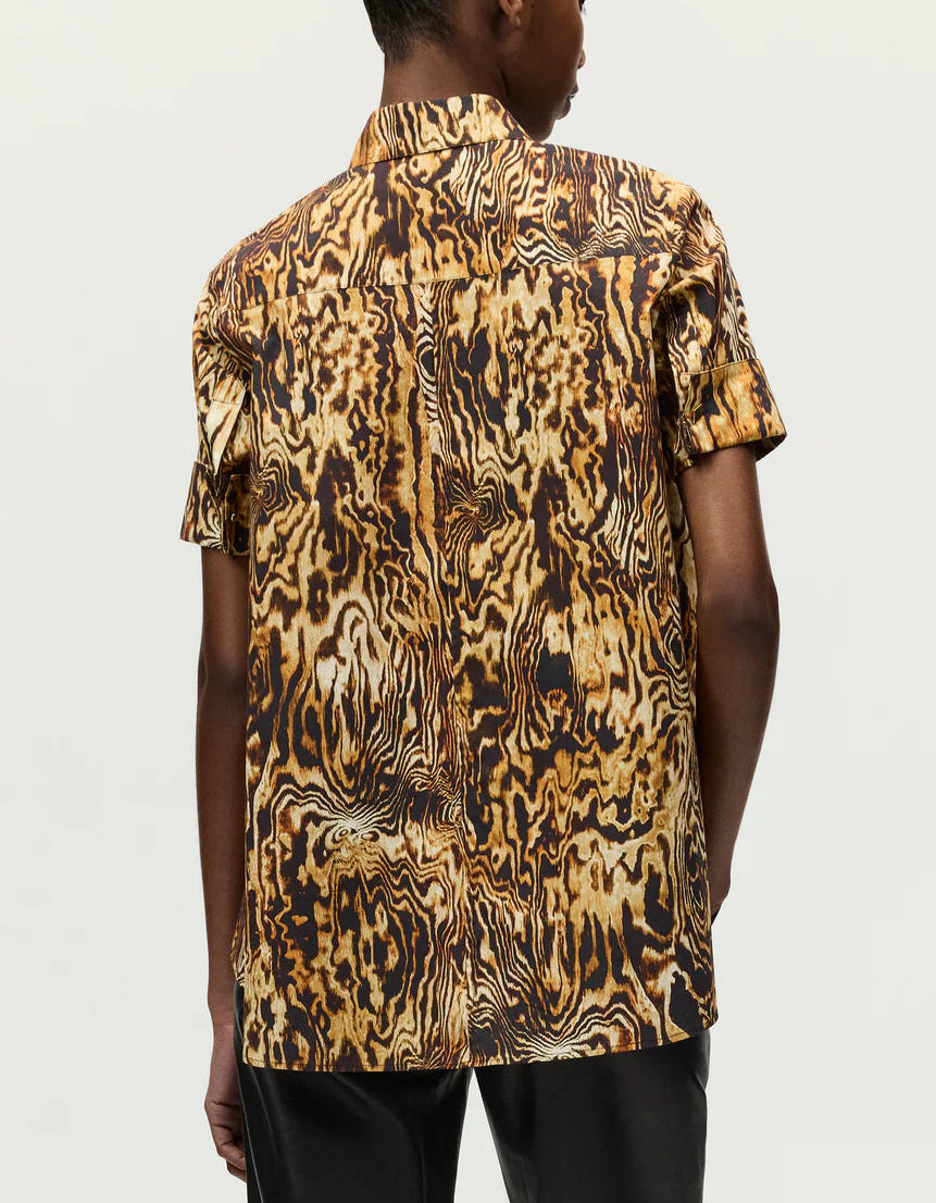 Person wearing the Charlie Top by Adam Lippes, a short-sleeve button-up with a collared silhouette and brown and yellow abstract woodgrain pattern, viewed from the back.
