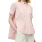 A person wearing the Adam Lippes Charlie Top, a pink and white striped collared blouse with a high-low hem, paired with white trousers.