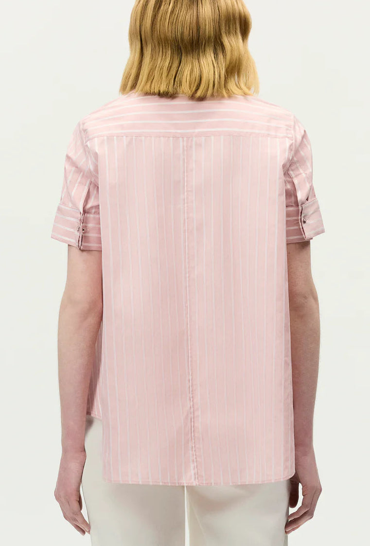 A person is seen from the back wearing the Adam Lippes Charlie Top—a light pink, short-sleeve, collared shirt with vertical white stripes.