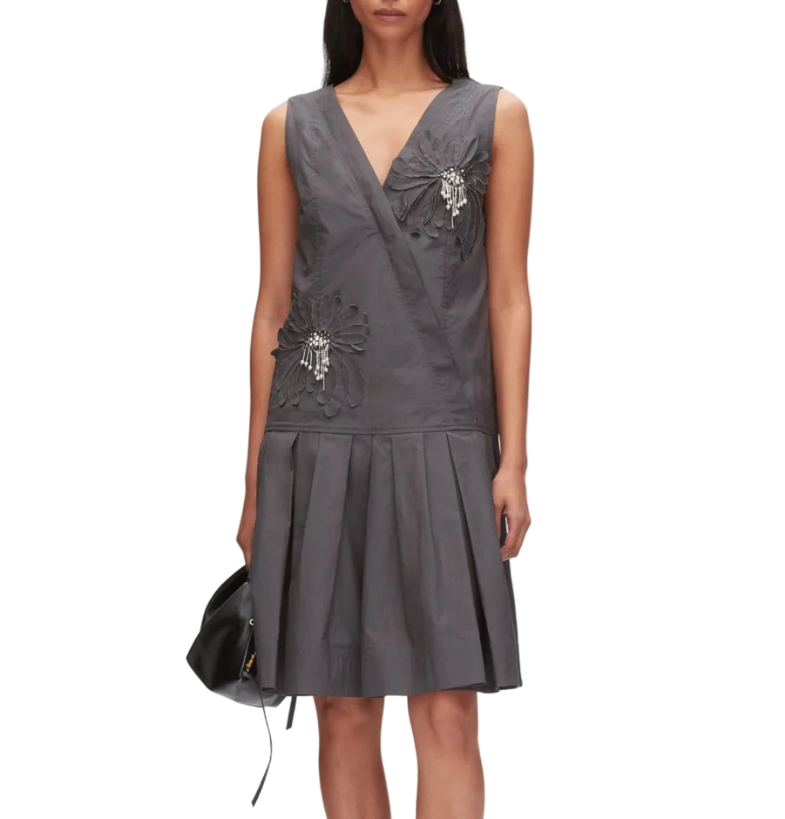 A woman stands against a white background wearing the 3.1 Phillip Lim Draped Tank Dress with Floral Applique, a sleeveless gray knee-length wrap dress adorned with floral appliqué and bead details, and holding a black handbag.