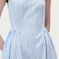 A person wearing the Aliena Dress by Adam Lippes, a sleeveless light blue shirtdress with thin vertical white and dark blue stripes, shown from shoulders to hips.