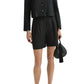 A woman wears the POSSE Marchello Short with a matching black button-up long-sleeve jacket, holding a black handbag and pairing the look with black pointed shoes.