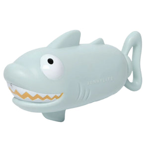 Introducing the Animal Soaker Shark Pastel Blue from Sunnylife, a light blue, shark-shaped novelty toy with a smiling face and cartoon features. This playful summer accessory comes with a handy tail handle and doubles as a delightful water squirter for aquatic fun.