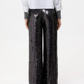 A person is seen from the back, wearing a white shirt and TWP's Adieu for Now Sequin Pant in black, against a plain background.