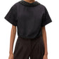 A person wearing the TWP Forever and Always Crystal Collar Shirt with short sleeves and dark high-waisted pants stands against a plain background.