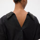 A person with their back to the camera wears the TWP Forever and Always Crystal Collar Shirt, featuring a deep V-shaped back, button details, and embellished shoulders.