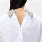 A person with long dark hair wears the TWP Forever and Always Crystal Collar Shirt, featuring an open back and crystal-embellished collar tips.