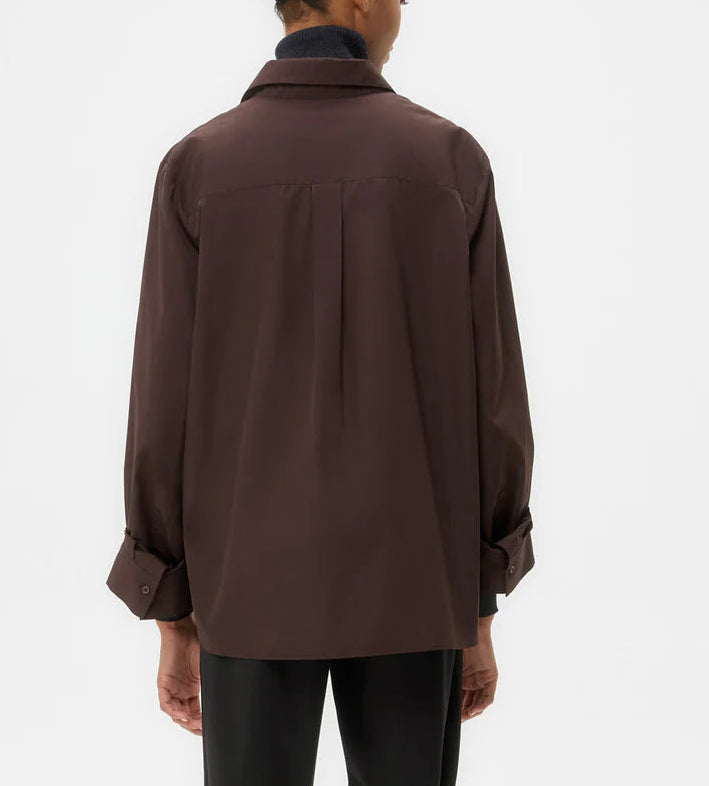 A person is seen from behind wearing the TWP Next Morning Shirt—an oversized brown Italian cotton button down with a relaxed fit and buttoned cuffs—set against a plain white background.