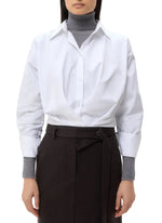 A person wears the oversized TWP Taken Shirt over a gray turtleneck sweater, paired with high-waisted black pants with a tie belt.
