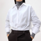A person wears the TWP Taken Shirt over a gray turtleneck sweater with high-waisted dark trousers; their face is partially out of frame.