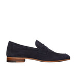 The Ann Mashburn Mia Suede Loafer is a navy blue Italian shoe with a rounded toe and low wooden heel, shown in side profile against a white background.